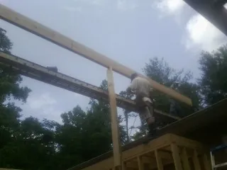 Carpenter setting a ridge beam over a new addition frame — Ice Dam Removal by Roofing Brothers in Persia