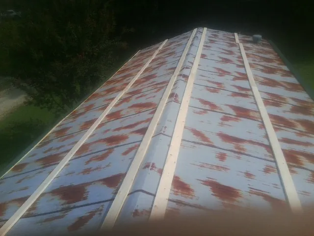 Rusted metal roof panels with new wood purlins before replacement — Storm Damage Roof Repair in Persia by Roofing Brothers