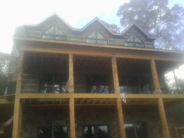 Dormers and porch framing on a large log home under construction — Roof Coating work by our crew in Persia