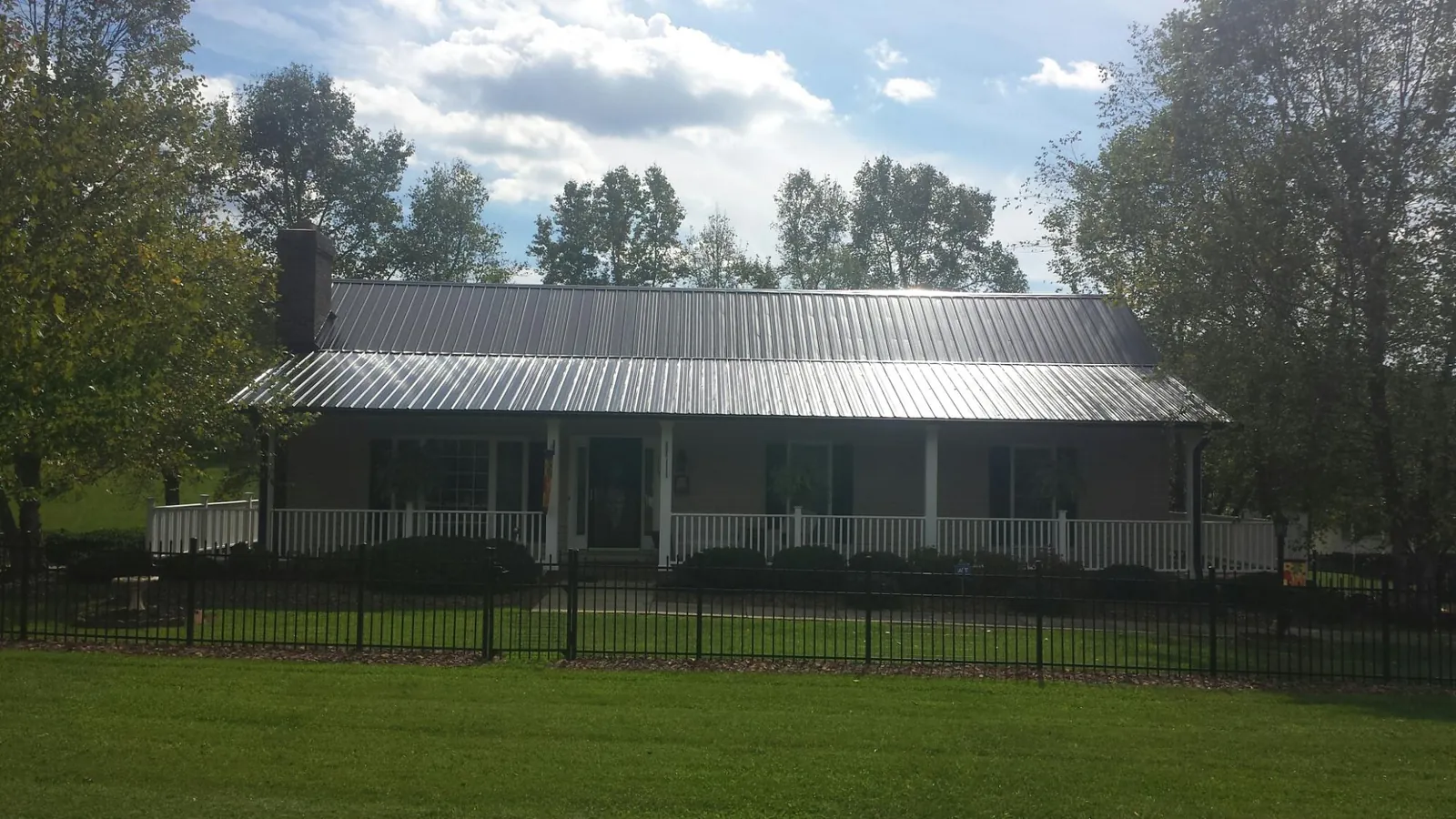 Gray metal roof on a brick ranch with a full width front porch — Gutter Guard Installation work by our crew in Persia