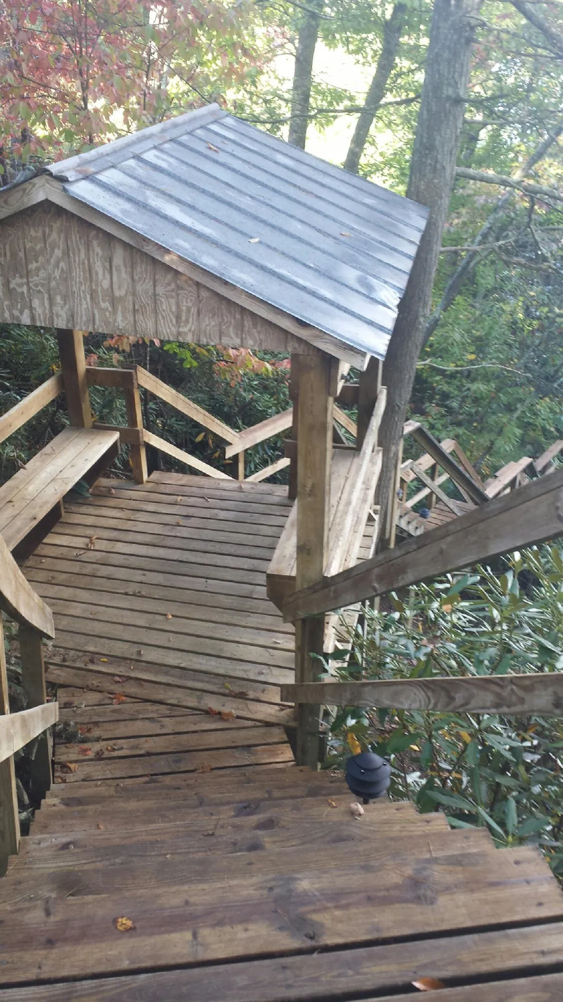 Metal roofed shelter over wooden steps on a wooded walkway — Skylight Repair & Installation work by our crew in Persia