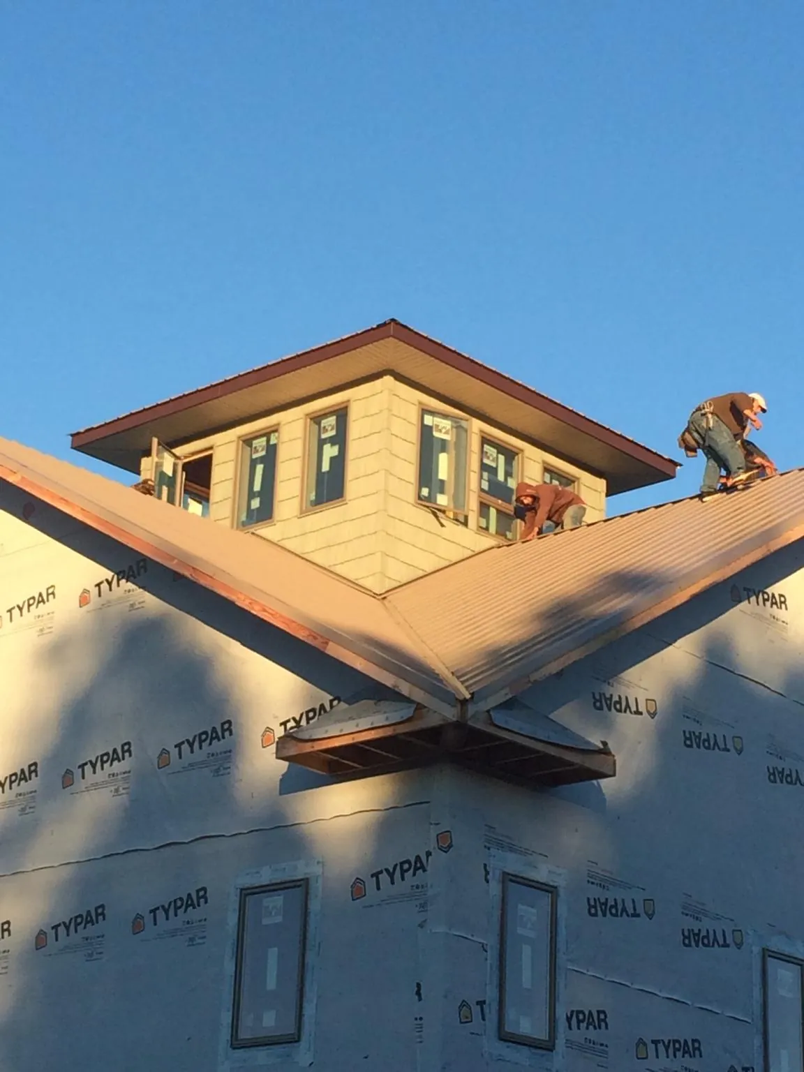 Roofers working around a rooftop cupola on a new metal roof at sunset — Roof Waterproofing in Persia by Roofing Brothers